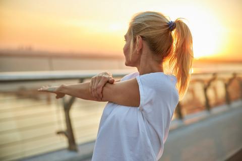 woman stretching shoulder outdoors
